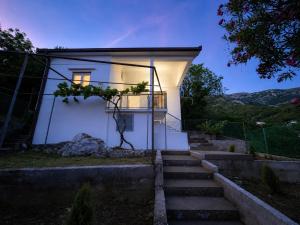 a small white house with stairs leading up to it at Apartmani Čanj in Čanj