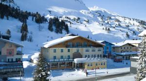 a group of buildings in the snow with a mountain at Hotel Wagner in Obertauern