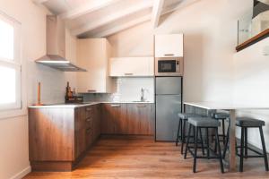 a kitchen with wooden cabinets and bar stools at Apartamento Porta14 3 Duplex in Chaves