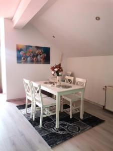 a white dining room table with white chairs and a vase of flowers at Apartman Nik-Rom 1 in Bosanska Gradiška +10 photos