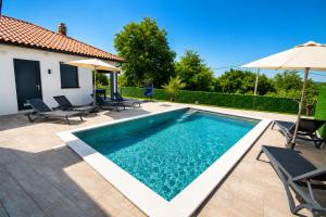 a pool with chairs and umbrellas next to a house at Villa Riviera in Nedeščina