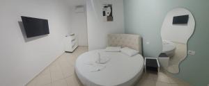 ein Badezimmer mit weißer Toilette und Fernseher in der Unterkunft Bluflest in Dhërmi