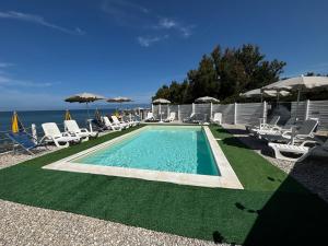 a swimming pool with chairs and umbrellas next to the ocean at Camping Victoria in Capaccio-Paestum