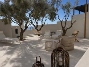 a patio with chairs and tables and trees at Syros-house in Azolimnos Syros