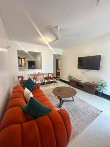 a living room with a orange couch and a tv at Diani Beach Modern Apartment in Diani Beach
