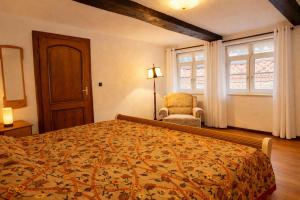 a bedroom with a bed and a chair and windows at Fachwerkhaus Bodenwerder in Bodenwerder