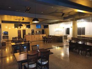 a restaurant with wooden tables and chairs and a kitchen at Green hillock hotel in Alwar