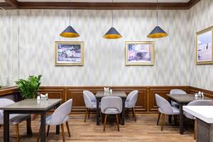 a dining room with tables and chairs and paintings on the wall at Rush Inn Hotel in Astana
