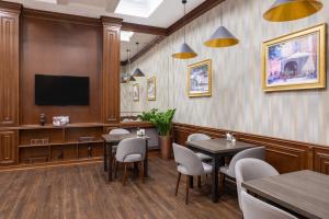 a waiting room with tables and chairs and a flat screen tv at Rush Inn Hotel in Astana