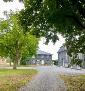 ein großes graues Haus mit einem Baum und einer Auffahrt in der Unterkunft Brændte Ege Gods in Nykøbing Falster + 12 Fotos