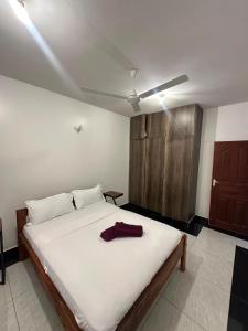 a bedroom with a large white bed and a wooden cabinet at Diani Beach Modern Apartment in Diani Beach