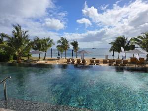 a swimming pool with chairs and the ocean in the background at Asmara Residence 2 Bedroom Apartment by LOV Mauritius, Beach Access in Petite Case Noyale