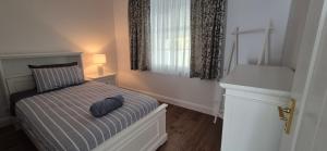 a bedroom with a bed with a blue pillow on it at Elegant White Cottage in Bomaderry