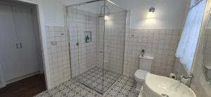 a bathroom with a shower and a toilet and a sink at Elegant White Cottage in Bomaderry