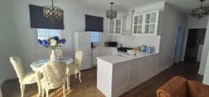 a kitchen with a table and chairs and a refrigerator at Elegant White Cottage in Bomaderry +4 photos
