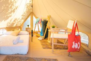 a tent with two beds and a chair in it at Kampaoh Praia do Meco in Sesimbra