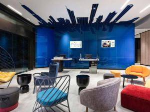 a lobby with blue walls and chairs and a table at ibis Styles Bangkok Sukhumvit 4 in Bangkok