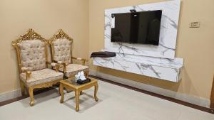 a living room with two chairs and a tv on a wall at Hotel Destination in Sukkur