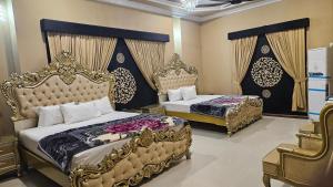 two beds in a bedroom with golditures at Hotel Destination in Sukkur