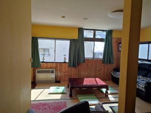 a living room with a table and some windows at PEUF Lodge in Otari