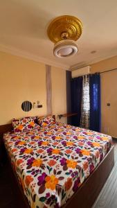 ein Schlafzimmer mit einem großen Bett und einer geblümten Bettdecke in der Unterkunft Résidence AELA in Banfora
