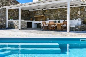 a pavilion with a table and chairs next to a pool at Lunar Villa in Glastros