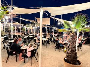 a group of people sitting at tables on the beach at night at Complex Turistic Perla Venusului in Venus