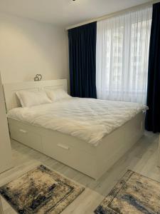 a white bed in a bedroom with a window at Ultracentral style apartment! in Craiova