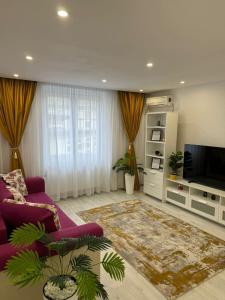 a living room with a purple couch and a tv at Ultracentral style apartment! in Craiova