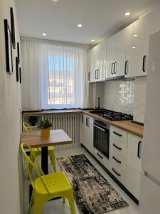 a kitchen with white cabinets and a table and yellow chairs at Ultracentral style apartment! in Craiova