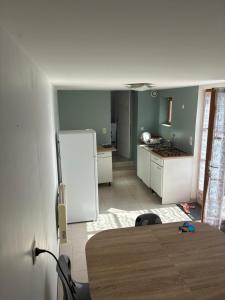 a kitchen with a table and a white refrigerator at Maisonnette in Chambon-sur-Voueize