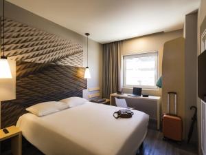 ein Hotelzimmer mit einem weißen Bett und einem Schreibtisch in der Unterkunft Ibis Torreon in Torreón