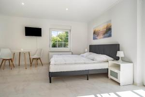 a white bedroom with a bed and a table at Feriendomizil Putbus - Nr. 3c in Putbus