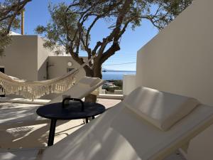 a white chair and stool on a balcony with a tree at Syros-house in Azolimnos Syros
