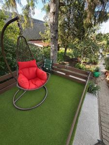 a red chair sitting on a patch of grass at Pop Apartment Kerepes in Kerepes +3 photos