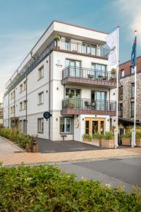 a white building with a flag on top of it at I love Sylt Hotel - adults only, hundefreundlich in Westerland