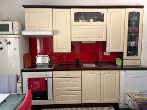 a kitchen with white cabinets and a red wall at Una Mirage in Bihać +12 photos