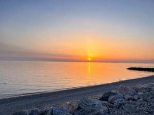 a sunset over the ocean with rocks on the beach at Residence Il Pantheon - Fuscaldoapartment in Marina di Fuscaldo