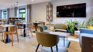 a restaurant with tables and chairs in a room at Campanile NATURE - Lille Lomme in Lomme