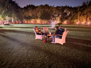 three men sitting on a bench in a park at night at TAG Farm in Greater Noida +4 photos