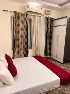 a bedroom with a white bed with red pillows at TAG Farm in Greater Noida