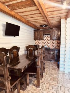 a dining room with a wooden table and a tv at Cottage Hata Zustrich in Bukovel