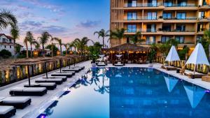 a hotel pool with lounge chairs and a hotel at Palmera Escape Radhime in Vlorë