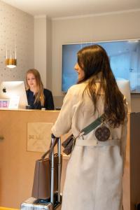 a woman standing at a counter with her luggage at I love Sylt Hotel - adults only, hundefreundlich in Westerland +46 photos