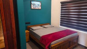 a small bed in a room with a blue wall at Rambos Inn Homestay in Vagamon