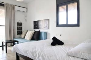 a bedroom with a white bed and a blue couch at Iinfinity home in Had Nes
