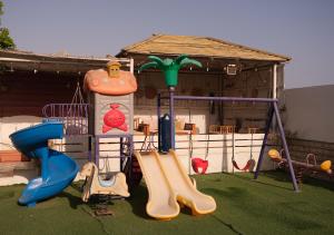 a playground with a slide and a swing at Sea Turtles Guest House in Al Ḩadd