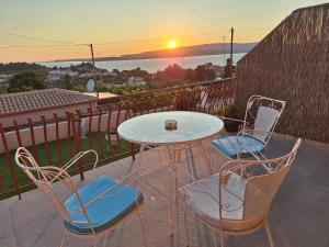 a table and chairs on a balcony with the sunset at LASSI Apartment 2 in Argostoli