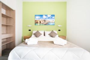 a bedroom with a large white bed and green walls at Piazza Pertini Rooms in Melendugno