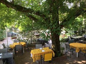 an outdoor restaurant with yellow tables and chairs under a tree at Logis Hotels - La Table d'Antan - Hôtel 2 étoiles et Restaurant in Bon-Encontre
